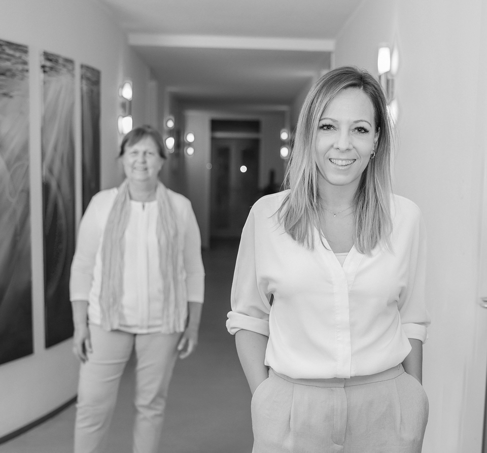 Die Zahnärztinnen Dr. Anja Kessler und Dr. Dorothea Sacher stehen in den Räumen der Zahnarztpraxis dental:ly 
